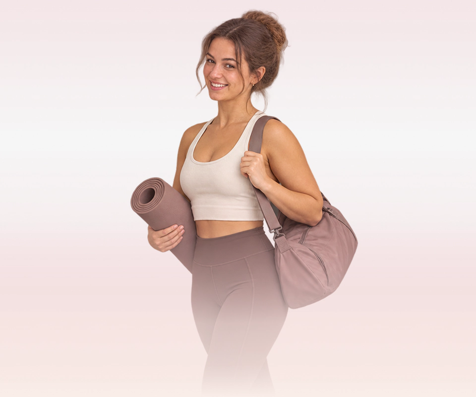 Lachende vrouw met yogamat en sporttas, klaar om zelfstandig verder te gaan
